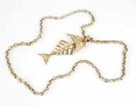 ALL SALES FINAL 71 A gold fish pendant on long chain An 18K gold skeletal fish pendant measuring 4'' x 2'' on an 18K bi-color gold mariners link long chain, Italy, 31'', 201.