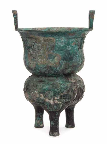 295* A Bronze Ritual Tripod Xian, the rounded, slightly waisted bowl having upright loop handles, with a band of bird and taotie, the tripod lower section having