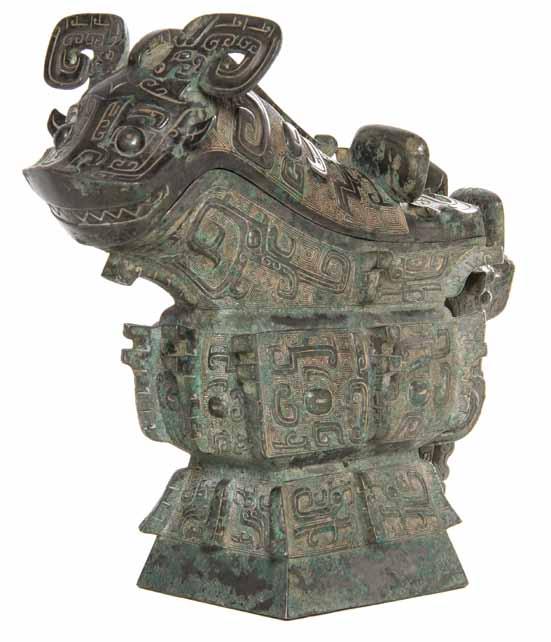 296* A Chinese Bronze Ritual Gong Vessel, the beast form vessel having a fitted cover depicting the animal s scrolled horns above protruding round eyes,