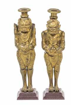 $200-400 358* A Pair of Bronze Oni Form Candlesticks, each having an urn form bobeche, one figure depicted with two horns, the other with a single horn, raised on stepped plinth bases.