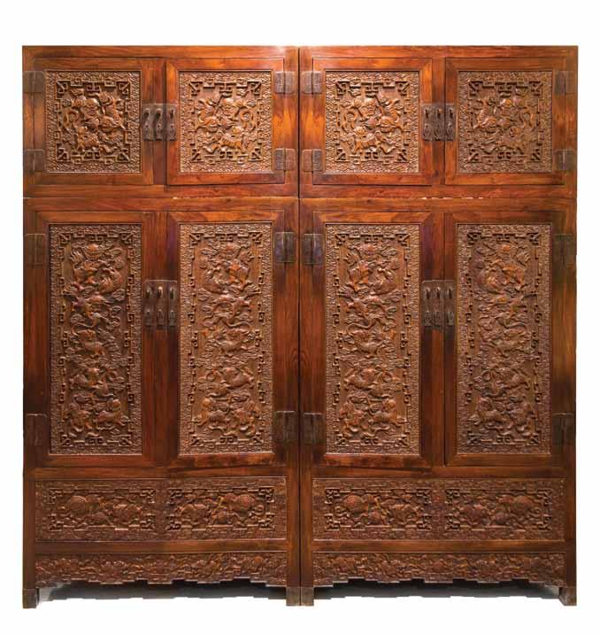 161 161* A Pair of Chinese Carved Hardwood Compound Cabinets, each cabinet door having relief carving depicting buddhistic lions chasing with a beribboned ball amongst ruyi clouds over a diaper