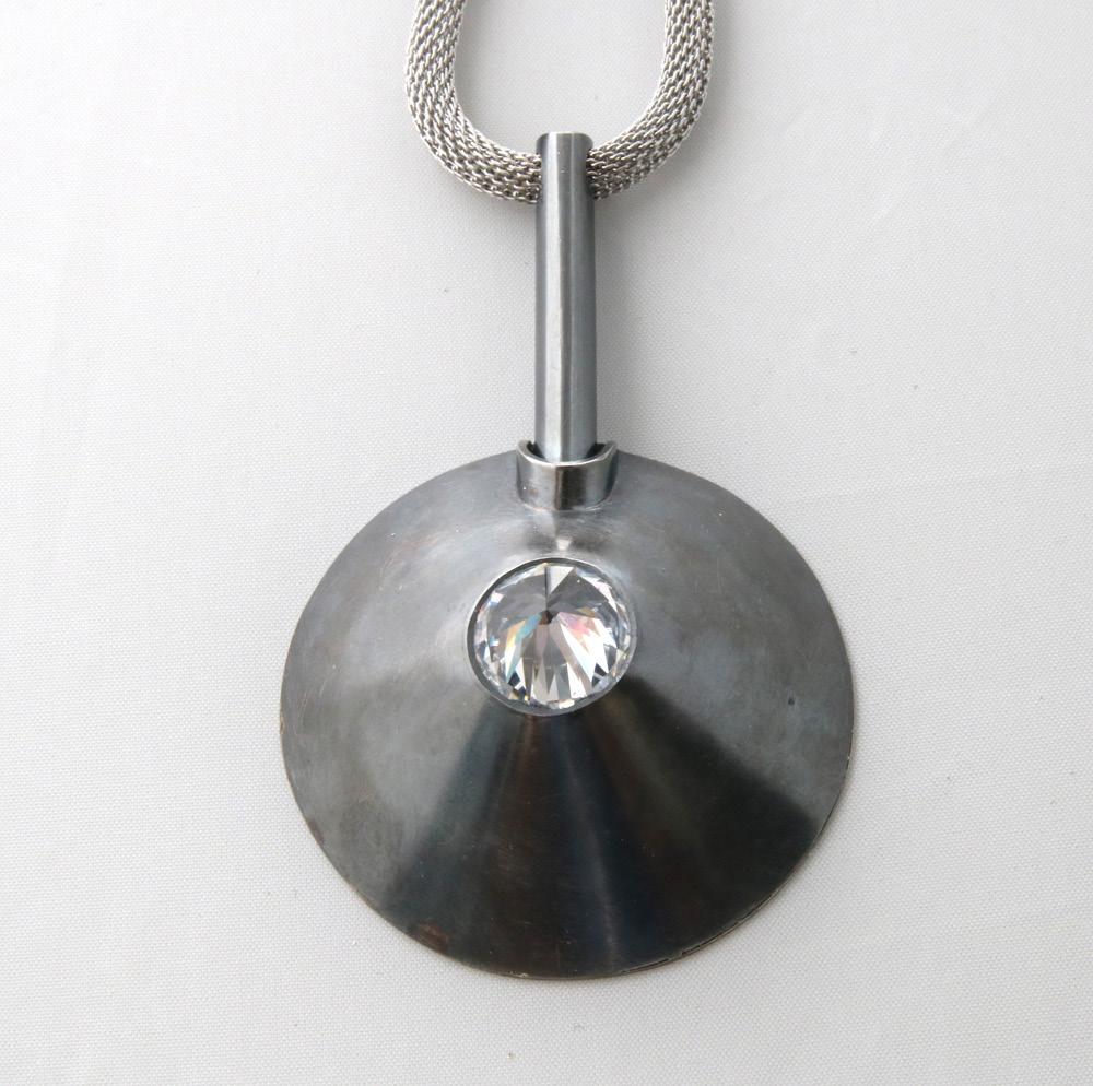 Christian Roux Montreal, QC Cone Silver, zircon, steel Clipped silver cone with diamond cut stone set inverted in its narrow opening and so completing the geometry of the cone.