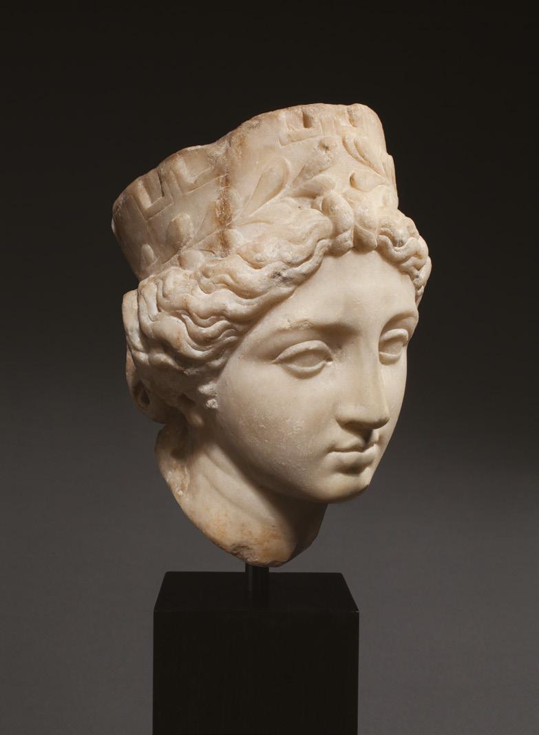 Roman head of Tyche-Fortuna 1st century BC Marble Height 17.5cm The goddess wears a mural crown with laurel wreath, the wavy hair centrally parted and drawn back in a bun.