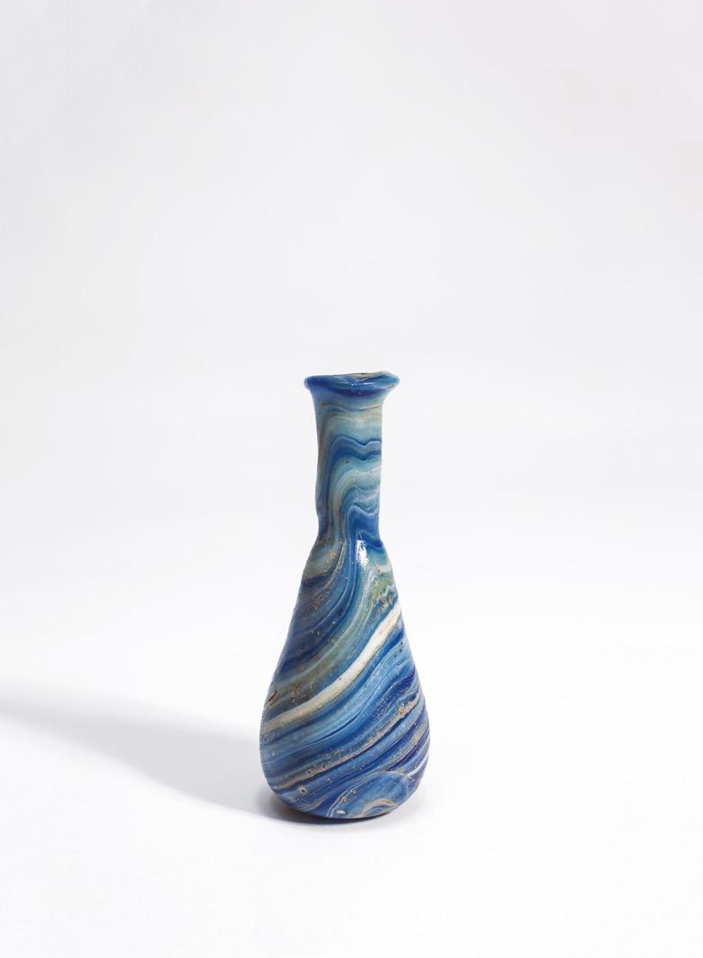 Roman unguentarium Eastern Mediterranean, c.1st century AD Glass Height 10.2cm With folded rim, and piriform body, the cylindrical neck constricted.