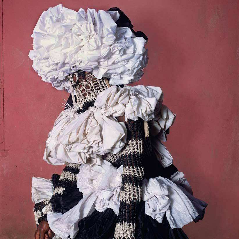 Okpo Masquerade This towering headdress and bodypiece are woven from fresh palm leaves twisted into points, intertwined with strips of white and red linen, and then stuffed with