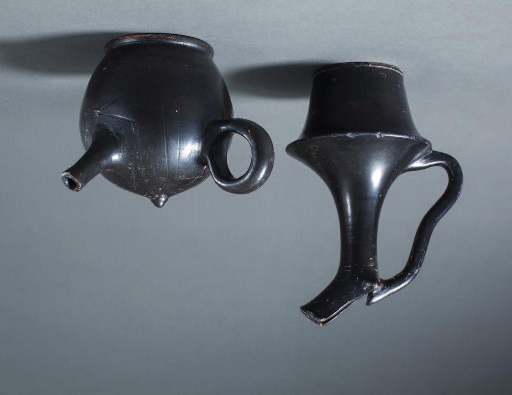 51.50 50 Greek black glaze oinochoe with tapering lip and narrow ribbon handle of an unusual meandering form. The sharply flaring shoulder quickly tapers towards the base, creating a kind of rim.