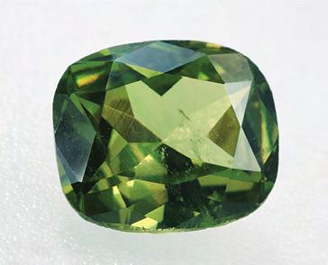 Figure 1. The demantoid crystal (9.01 9.42 mm) and 1.98 ct faceted cushion cut are from the Sferlùn mine in Val Malenco, Italy.
