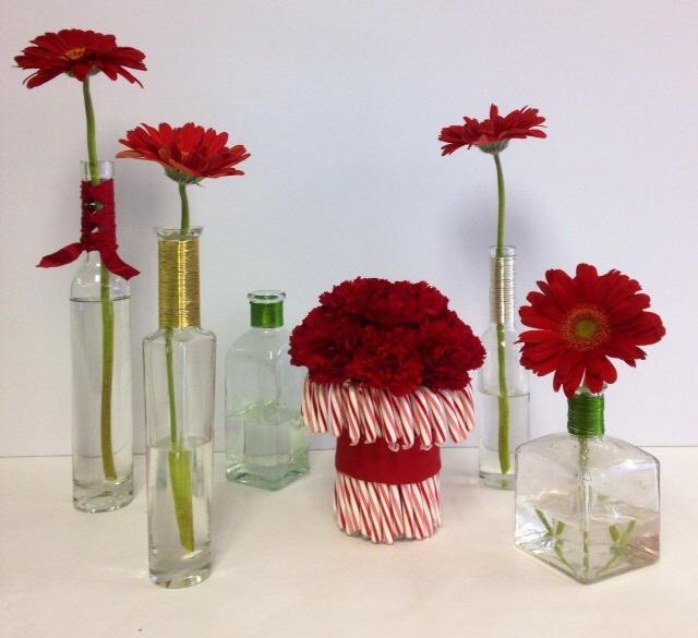 Winter Christmas: Assortment Centerpiece Flowers/Supplies needed: 5 Assorted vases (olive oil bottles and bath products bottles), but may use whatever 4 Red gerbera daisies #3 red ribbon (dependant