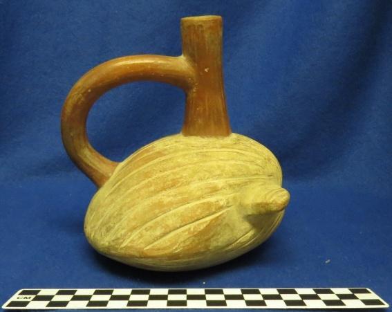 A. Brown Author s Description: Red and cream-colored spout-and-handle bottle of shell. Measurements: Height of Vessel = 15.7 cm Height of Body = 8.5 cm Length of Vessel = 13.2 cm Width of Vessel = 13.