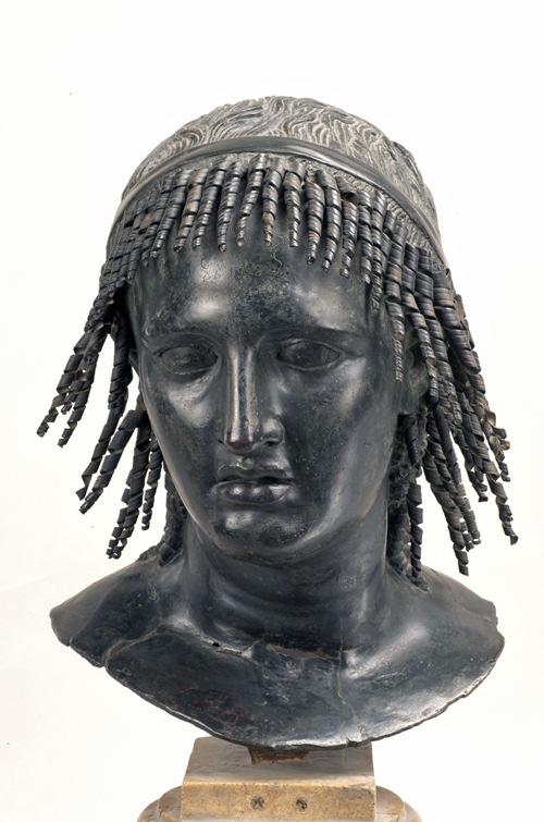 Title: Woman with Corkscrew Curls ( Tolomeo Apione ) Date / Period: 154-196 CE Origins: Herculaneum Inv.N: 5598 Medium: with applied copper curls Size: 41 x 31 cm Base: H. 20 x D.