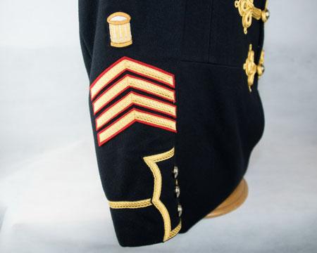 chevrons (gold on red) surmounted by an embroidered drum (gold on dark blue) Lower right arm - centrally, lowest point of chevron 10mm above