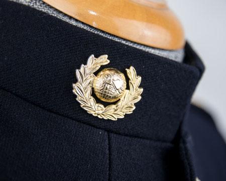 fastening edge set 5mm above the collar seam with the centre of the badge 50mm from outside