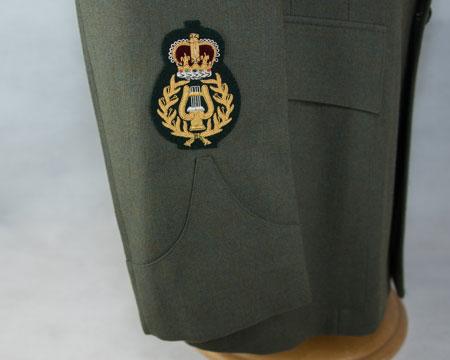 Bandmaster rank badge: Embroidered lyre in laurel wreath, surmounted by crown (gold on green) Effective October 2017 Lower right arm - centrally, bottom edge of badge 10mm above top of sleeve slash