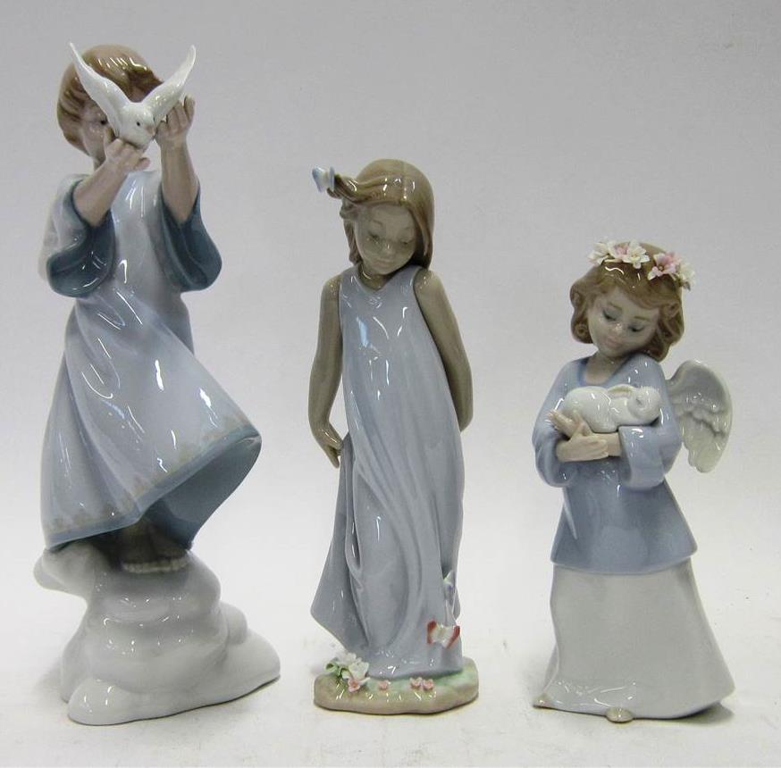 183 THREE LLADRO PORCELAIN MODELS OF CHILDREN Comprising: one Lladro Privilege girl in a red cape; one boy holding a bird aloft; and a model of a girl and a