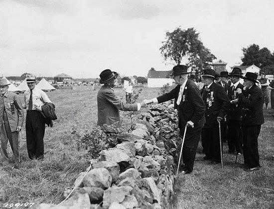 Confederate and Union soldiers shake hands across the wall at