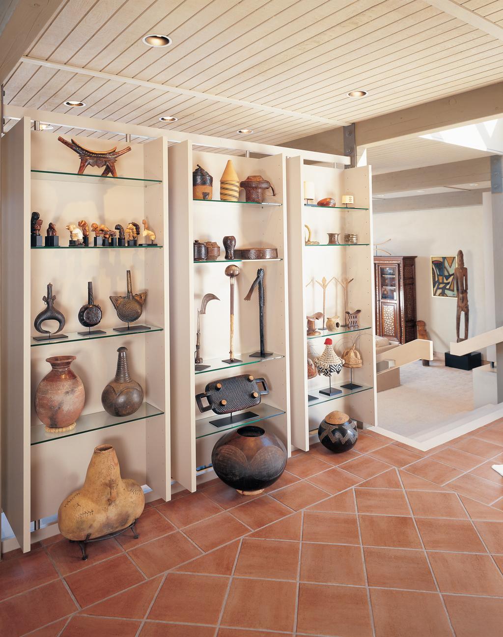 Shelves in the entry hallway adjacent the living room showcase, left (top to bottom), a Dinka stool from the Sudan; Indonesian and Malaysian kris handles associated with the Muslim tradition; three