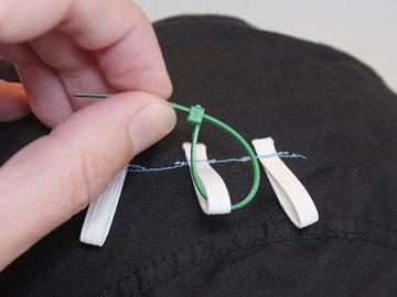 Put a small cable tie through one of the elastic loops, then start to close it on itself.