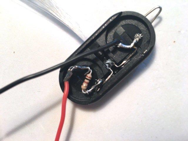 Open the glowby up and pull out the batteries. Bend the LED leads up and solder a 100 ohm resistor to the positive lead, and a red wire to the other side of the resistor.