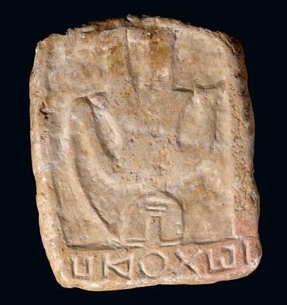 103 A SQUARE RELIEF WITH INSCRIPTION With a crude schematic figure holding a curved implement, possibly a bow, a Greek inscription reads across the top of the fragment, 14.