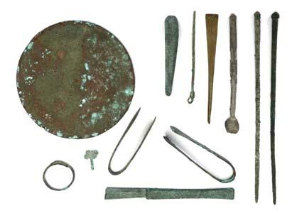 D. Including a mirror with incised concentric circles and ridges; pins, two pairs of tweezers, the scoop of a small strigil; and other bronze implements; a spiral ring; and an
