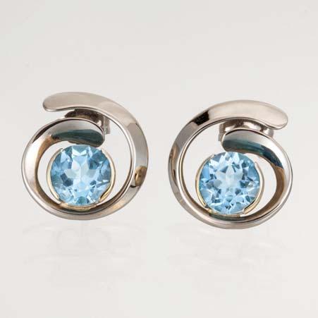 in 14kt White Gold Item # 3955 ALU: E186GBW Blue Topaz Description: 14kt White Gold Hand Forged Two Rd 7mm Blue Topaz Partial Bezel Set Forged Overlap Design Post and