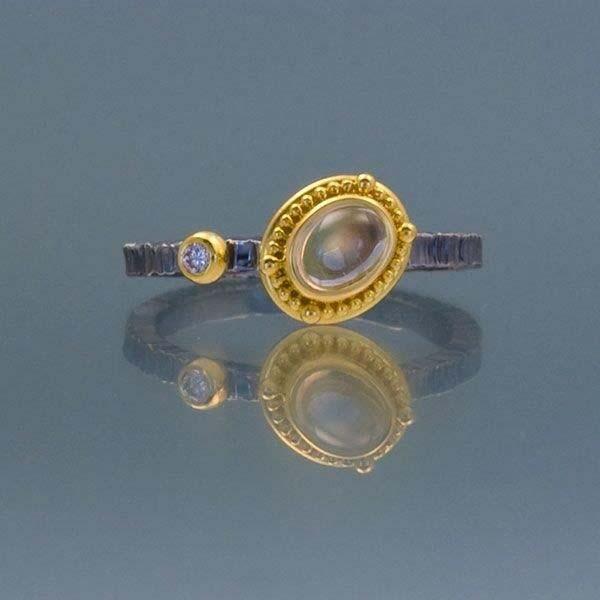 70ct set at an angle, almost horizontally, in a decorative bezel. Bezel is decorated with hand fabricated granulation. One Pink Sapphire of 0.04ct is bezel set to the left of the Moonstone.