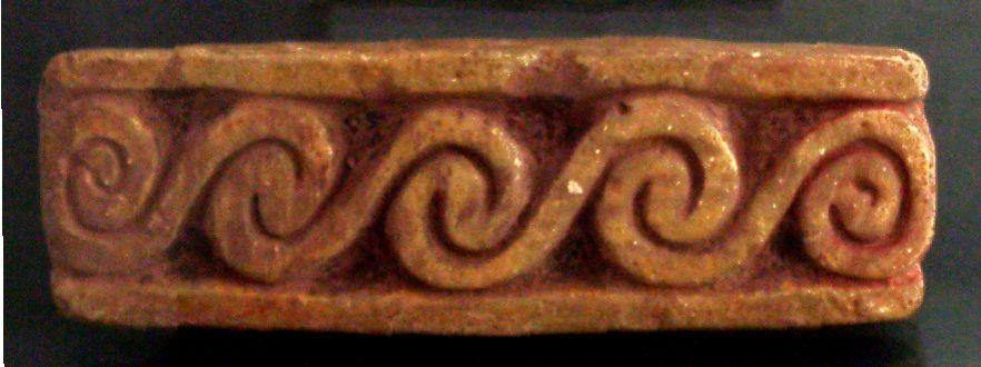 0)], via Wikimedia Commons Image: Carved clay stamp (pintadera); image shows surface with