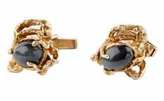 7mm 500-700 103 A pair of gentleman s cufflinks, Arthur King each claw set with a cabochon black cats-eye sapphire, in a stylised asymmetric surround,