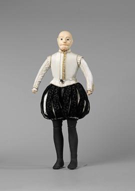 19. Tie doublet ribbon point at the waist, centre front. 21. Take his neck ruff and tie at the front using the white thread. It should sit tucked under the doublet collar. 20.