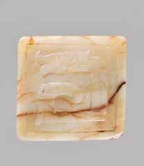 to the left in a finely incised square-cut frame, verso with plain recessed base. The edges with rectangular openings. Creamy white jade with dark brown inclusions and veining, smooth surface polish.