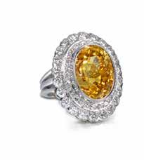 65 64 66 64 A YELLOW SAPPHIRE AND DIAMOND CLUSTER RING The oval-cut yellow sapphire, collet-set within a double-tier surround of brilliant-cut diamonds, sapphire weighing approximately 33.