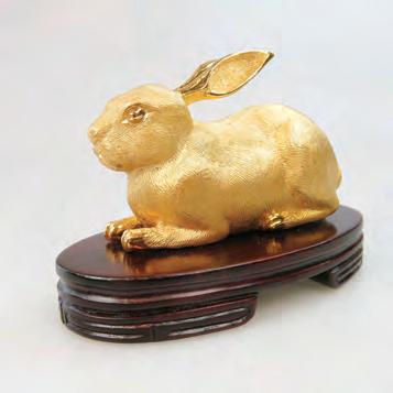 12.2 grams, with the original box $400 600 $1,400 1,800 328 24K YELLOW GOLD FIGURE OF A RABBIT on a wooden base, 69.