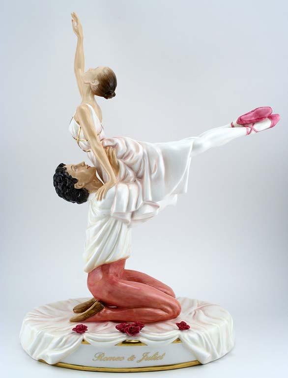 Romeo is kneeling on a draped base sprinkled with roses as he lifts the lovely Juliet into a graceful pose. Romeo and Juliet is written beautifully on the side of the base in an elegant gold script.