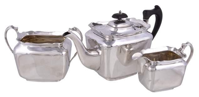 21 21 An Edwardian silver rounded rectangular three piece tea service by Lee & Wigfull, Sheffield 1906-07, the tea pot with a black composition oblong finial and handle, 27cm (10 1/2in) long, 1106g