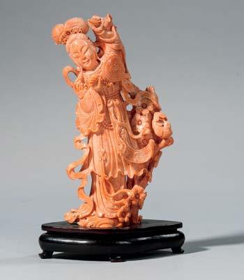 281 Coral Carving of Guanyin, China, 20th century, standing on a lotus base, with her hands crossed at her belly, pointed arch halo around her head, with wood stand, ht. 3 7/8 in.