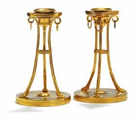 269 a pair of french empire gilt bronze candlesticks, each with tapering angular stem on paw feet, round arched bases. early 19th century. H. 26 cm.