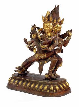 329 Buddhist part gilt large copper yab yum figure of a crowned three headed Mahakala with consort, standing on a lotus throne. 20th century. H. 102 cm.