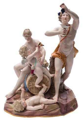 641 A large Meissen porcelain bacchanalian group in the form of Bacchus holding aloft a bunch of grapes in one hand, a goblet in the other, a nymph and three putti around a barrel