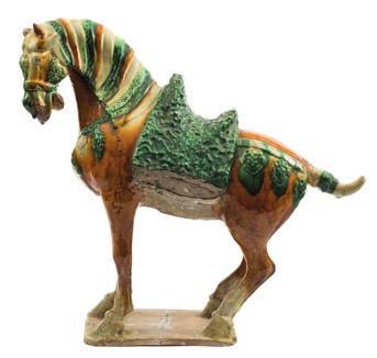 525 A Chinese pottery model of a caparisoned Fereghan horse decorated in sancai glazes, standing four-square and wearing a saddle, it s head turned