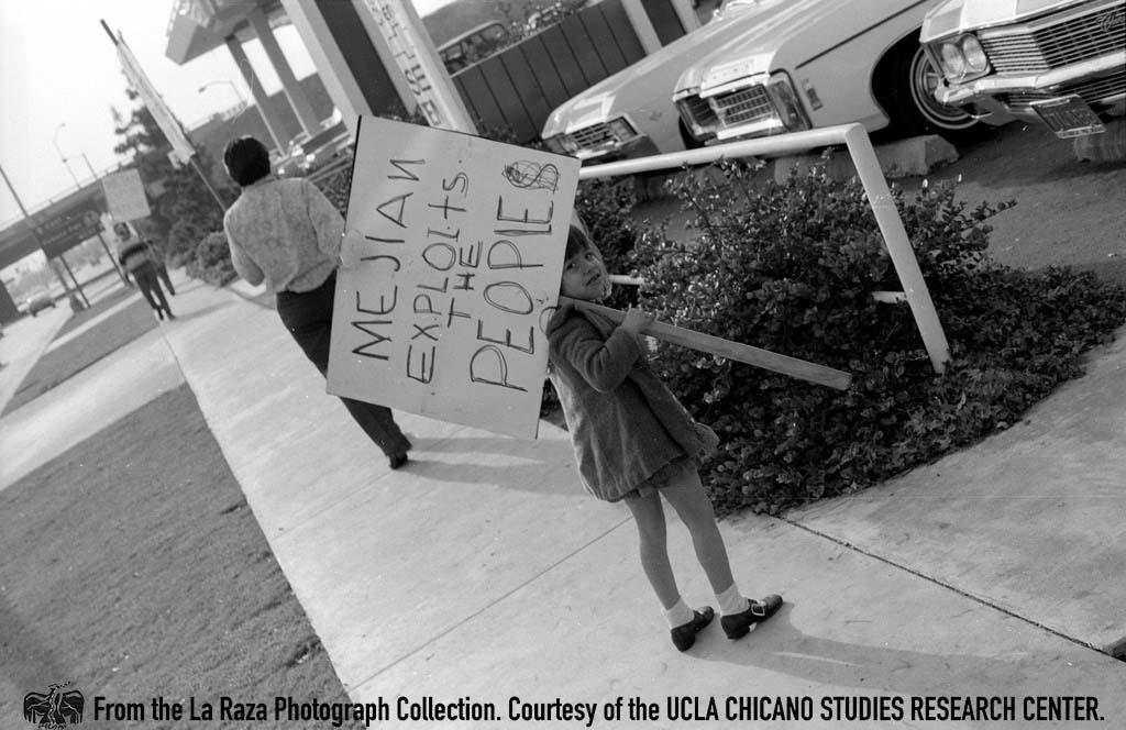 Child holds protest sign on the street corner outside Mejian Chevrolet La