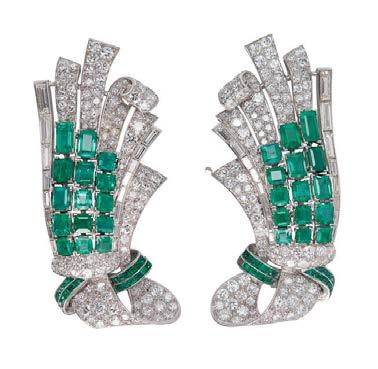52cts 300-500 44 HC936/1 An emerald and diamond set brooch of stylised scrolling design, set throughout with graduated round and baguette cut diamonds, with a curved detail of graduated