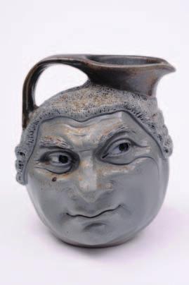 96 431 A Martin Brothers salt glazed stoneware double sided Barrister jug the grey body modelled with a wigged and smirking visage applied with