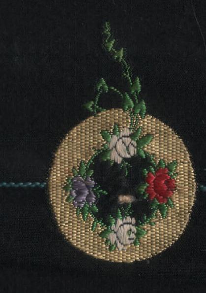 This example shows a polychrome floral design on a black taffeta ground. This design runs across the ribbon rather than with the length of the ribbon which was more common.