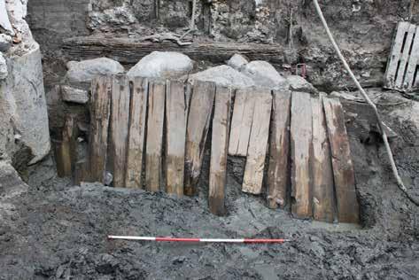 possibly with a peg. These beams were covered by steeply angled planks which appear to have been partly driven into moat silts below.