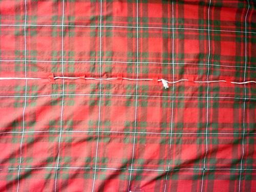There are 14 tapes approximately 1 long x 0.5 wide crudely sewn along the length of the plaid, 7 either side of the central unsown section.