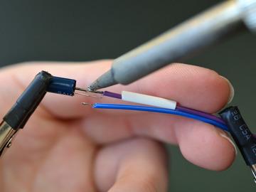 Apply a small piece of heat shrink tubing and reflow the solder between that wire and