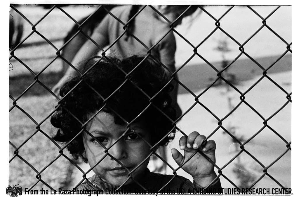 Young boy behind chainlink fence La Raza photograph