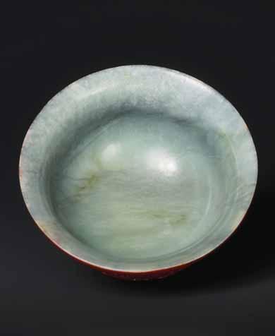The jade bowl is delicately carved to perfection, with a flared rim and an accentuated round foot.