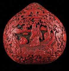 254 a cinnabar Lacquer covered Box of circular form, carved in relief showing a standing fu lion clutching a beribboned brocade ball circled by rushing waves. Diameter 7 inches.