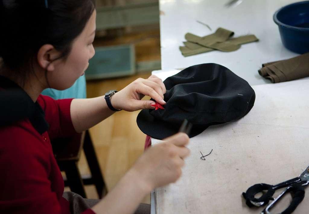 A tailor makes a cap with the iconic communist red star.